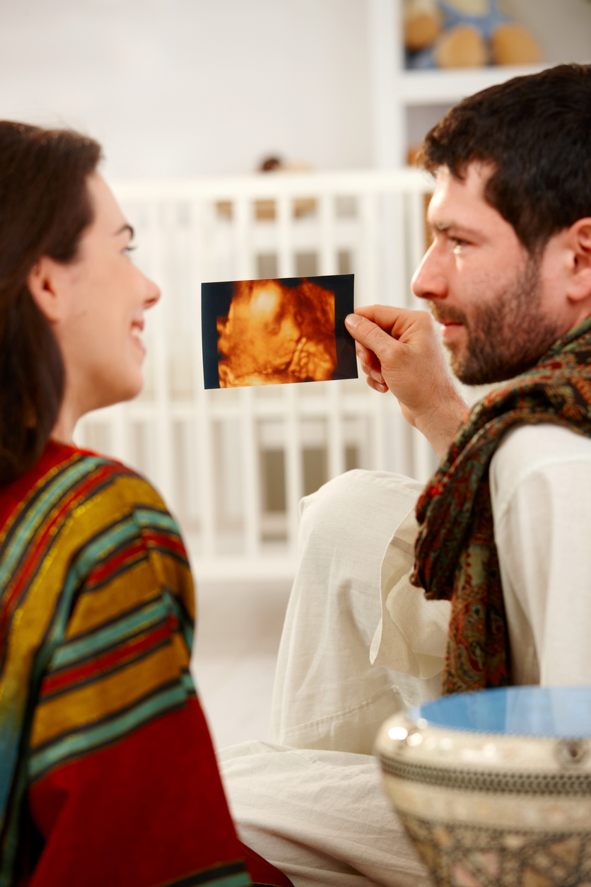 Young couple holding baby ultrasound image